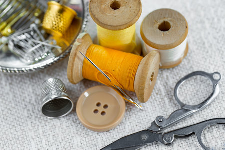 Spools of thread, scissors, thimble and buttons on the table