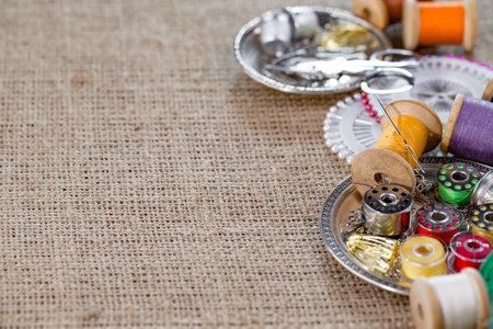 Sewing accessories on a burlap background. Sewing kit. Thread, needles, buttons, thimble.の写真素材