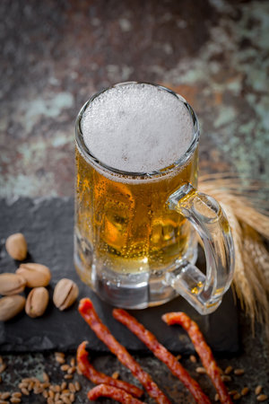 Light beer in a glass and sausages on a dark backgroundの写真素材