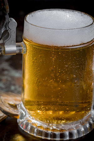 Beer in a glass with foam on a dark background close-upの写真素材