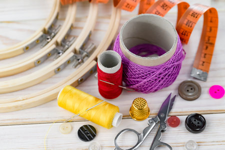 Spools of thread, scissors, buttons and other sewing accessories on wooden background