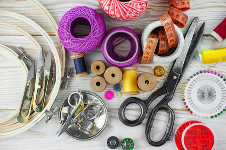 Sewing accessories on a wooden background. Sewing kit, scissors, thread, needles, buttons and fabric.の写真素材