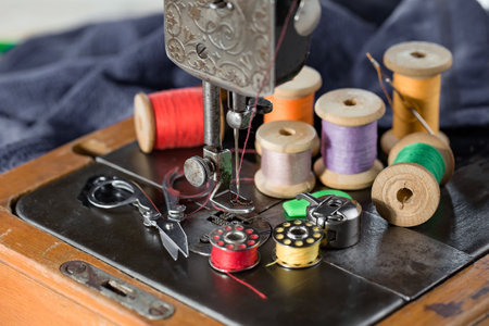 Sewing machine with threads and buttons on a wooden table.の写真素材