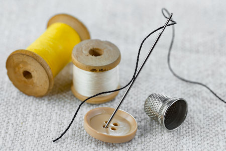 Sewing accessories: thread, needle, thimble on a white background