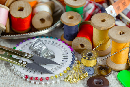 spools of thread, scissors, pins and buttons on fabric backgroundの写真素材