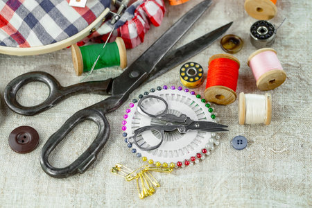 Sewing tools and accessories for needlework on a fabric background