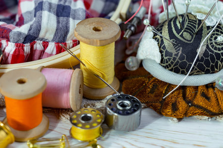 spools of thread, buttons and fabric on a white wooden backgroundの写真素材