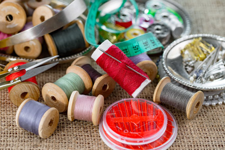 Spools of thread, scissors, buttons and sewing accessories on sackclothの写真素材