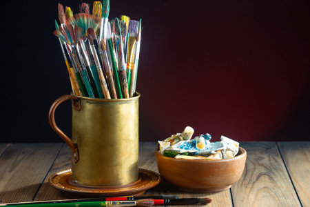 Paint brushes and paints in a cup on a wooden table.の写真素材