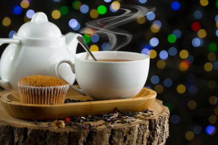 Cup of tea with muffin on wooden table on bokeh backgroundの写真素材