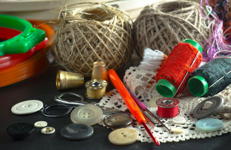 Sewing accessories on a black background. Threads, scissors, buttons and needles.の写真素材