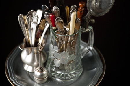Vintage silverware in a glass jar on a black background.の写真素材