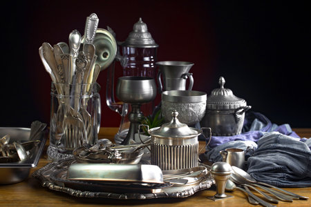 Antique silverware and utensils on wooden table over dark backgroundの写真素材