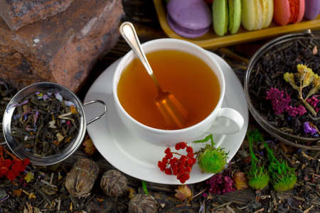 Tea in a cup on a saucer on a background of green tea leavesの写真素材