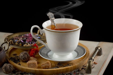 Tea in a cup on a saucer on a black background.の写真素材