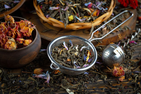 Dry tea leaves with rose petals in a bowl and strainerの写真素材