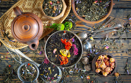 Dry tea leaves in a bowl and teapot on a wooden tableの写真素材