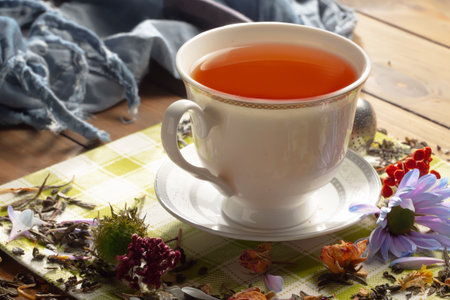 Cup of tea on a wooden table with a scarf and flowersの写真素材