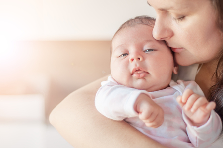 Mother with her newborn baby. Mother is holding her little baby girl.  Photo with the effect of sunlight, soft natural light, with selective focus.の写真素材