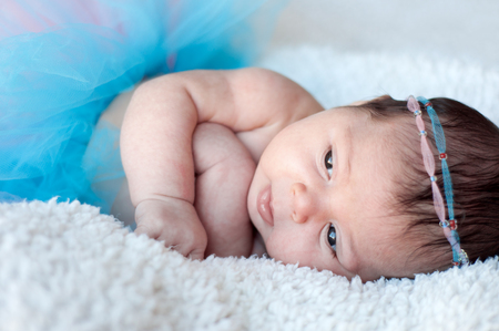 Newborn baby girl. Portrait of a newborn girl with a fluffy skirt and the pink - blue Headbands with beads.の写真素材