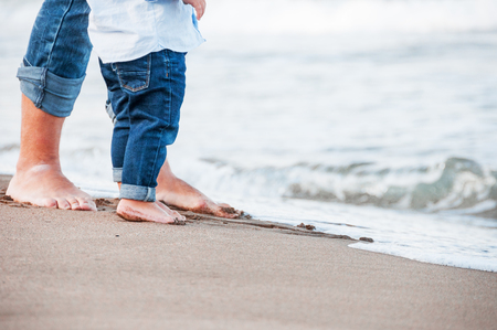 Bare feet of child and adult on the sea. vacation concept. Happy family concept の写真素材