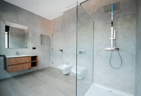 Modern bathroom with a glass bathtub and luxury washbasin. The walls and floor are covered with modern tiles. の写真素材