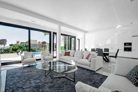 Luxurious and modern living room, dining with large windows with access to the pool. . Luxurious furniture, sofa, table and chairs.のeditorial素材