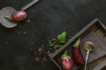 Eggplant varieties in black bowl over dark slate background. Overhead view.の写真素材