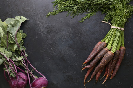 Ripe black carrots. Dark stone background. Autumn harvest.の写真素材