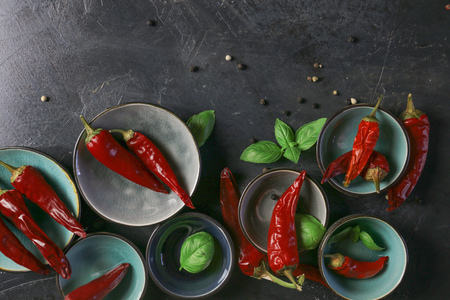 chili peppers with basil and peppercorns in bowls on a rustic surface,の写真素材