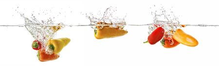 Paprika in red, orage and yellow fall into the water, panoramaの写真素材
