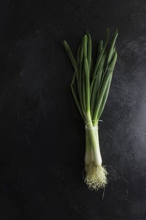 Spring onions on dark tableの写真素材