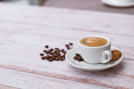 Cup of coffee with beans on a light wooden table.の写真素材
