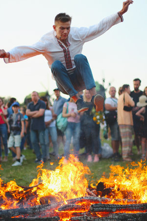 KYIV, UKRAINE - JULY 6, 2018: Young man jumps over the flames of bonfire during the traditional Slavic celebration of Ivana Kupala holiday in Pirogovo open-air ukrainian folk museumのeditorial素材
