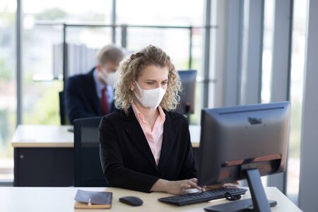Business woman with curly blonde hair wearing a mask sitting in office, Concept,contagious disease, coronavirus, covid2019の写真素材