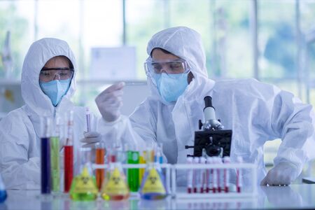 Male scientists and white female scientists are experimenting with chemicals in the laboratory. Concept, The scientists wear white protective clothing is experimenting with drug anti- Coronavirusの写真素材