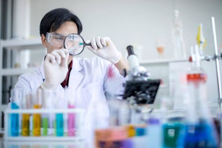An Asian male scientist wore a white coat to test the ARV, a drug research laboratory. Concept, Scientists are experimenting with antiviral drugs or Covid 19.の写真素材