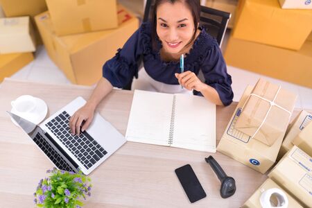 Top view, Asian women who are SME online shopping operators siting and looking at the camera. Online shopping SME entrepreneur or freelance working concept.の写真素材