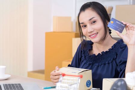 Asian women who are online shopping operators SME smile confidently and holding credit card on hand,...