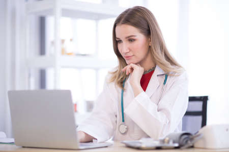 The female doctor wore a white robe with headphones and look at to laptop.の写真素材