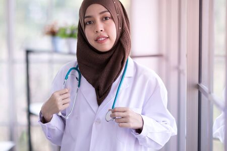 Close-up of a Muslim female doctor with stethoscope, and smiling confidently and looking at the cameraの写真素材