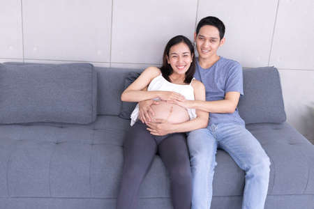 Pregnant women and Asian couples sitting on the sofa in the living room in the house, Concept...