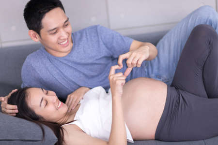 Pregnant women and Asian couples sitting on the sofa in the living room in the house, Concept...