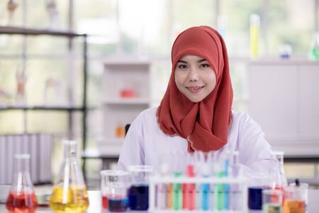 Female muslim scientists in white gown looking at camera and smile  and there have test tube on tableの写真素材