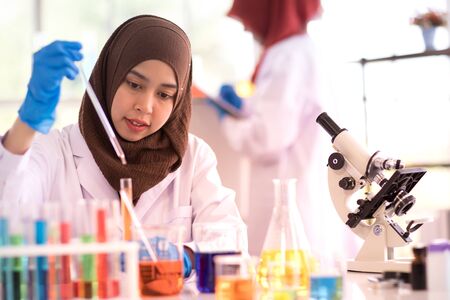 A female muslim scientist in white gown holding test tube in laboratoryの写真素材