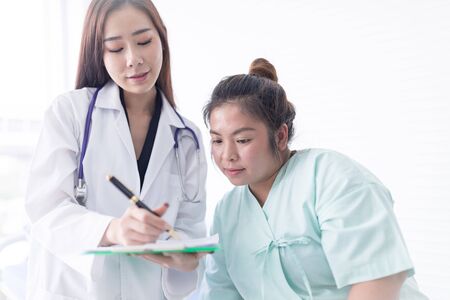 Asian female doctor is describing the diagnosis of female patients regarding obesity. Medical and health conceptsの写真素材