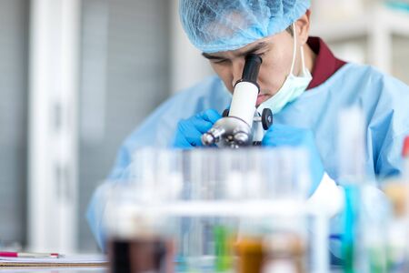 Asian scientists are looking for microscopes while doing medical research in a science laboratory.