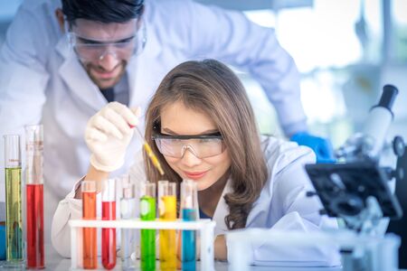 Male scientists and white female scientists are experimenting with chemicals in the laboratory....