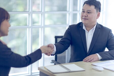 Two Asian business wears a black suit and hand in hand with a partner and smile confidently.  Asian business concept.の写真素材