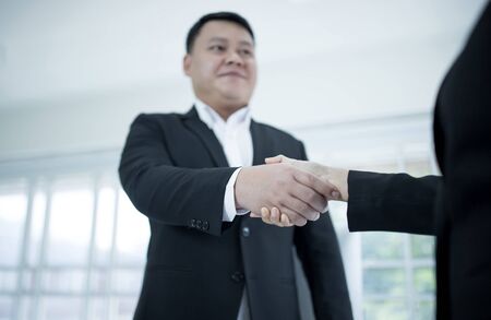 Asian businessman wears a black suit and hand in hand with a partner and smile confidently.の写真素材